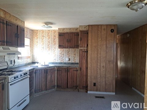 A kitchen with wooden cabinets and a white stove top oven.