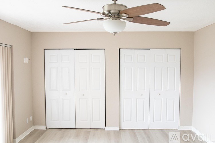 A room with a ceiling fan and two white doors.