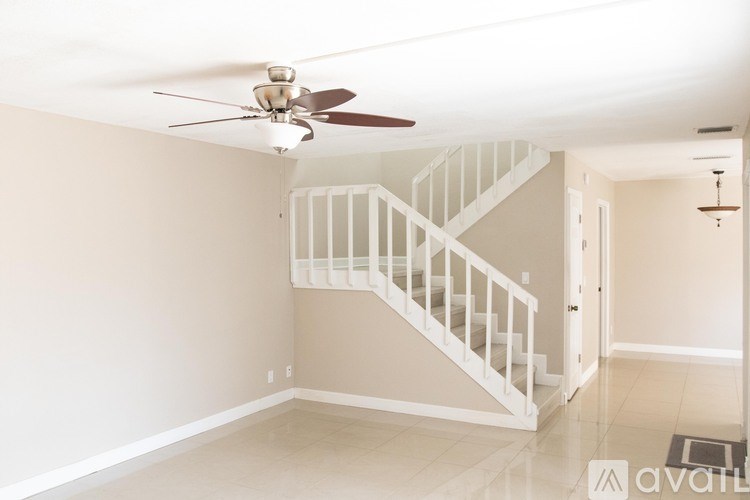 A room with a staircase and a ceiling fan.