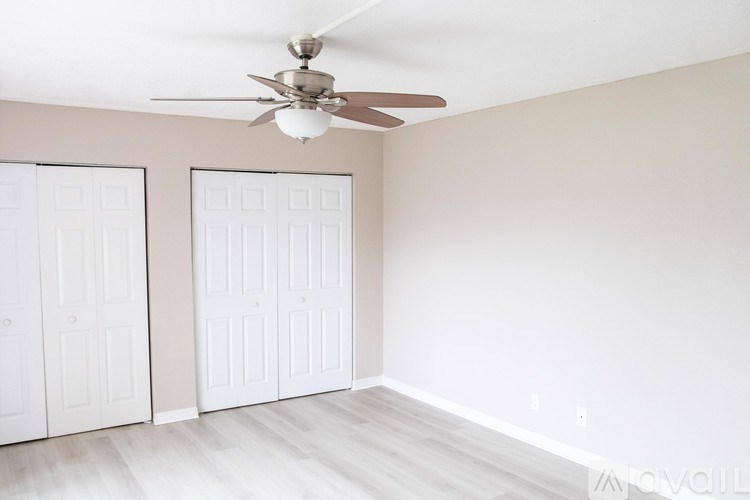 A room with a ceiling fan and two white doors.