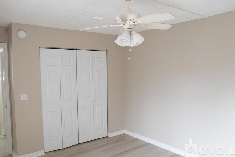 A room with a ceiling fan and a white door.