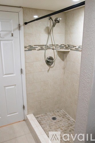 A bathroom with a white door and a tiled shower area.