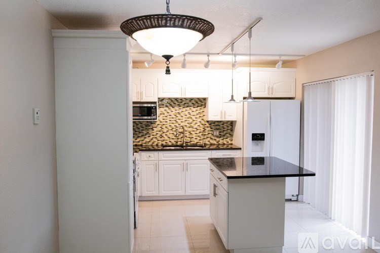 A kitchen with a black countertop and white cabinets.