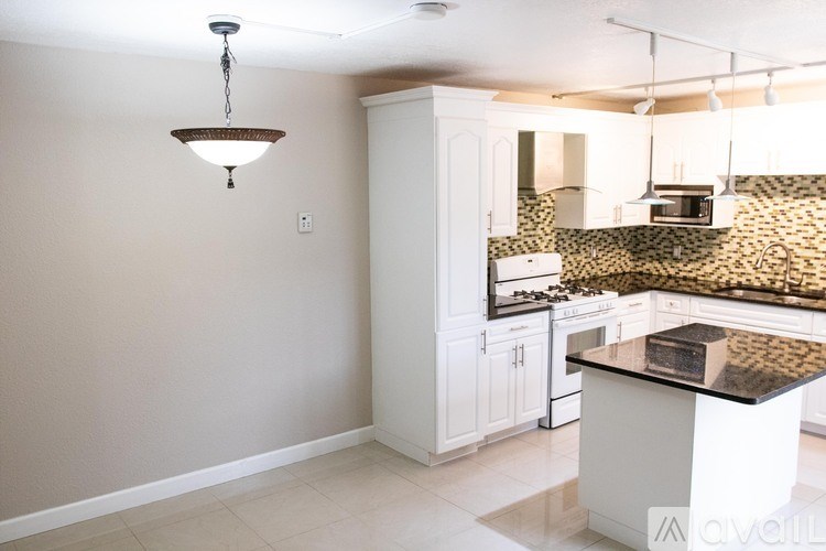 A kitchen with a white cabinet and a black counter top.