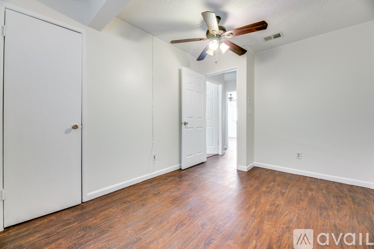 A room with a ceiling fan and wooden floors.