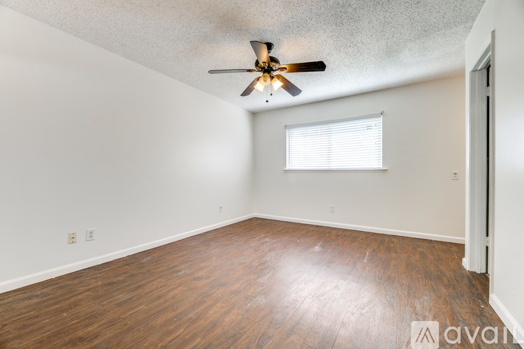 A room with a ceiling fan and wooden flooring.