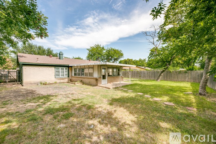 A house with a green fence and trees around it.