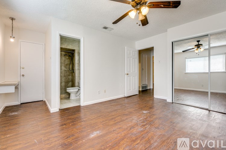 A room with a ceiling fan and wooden floors.