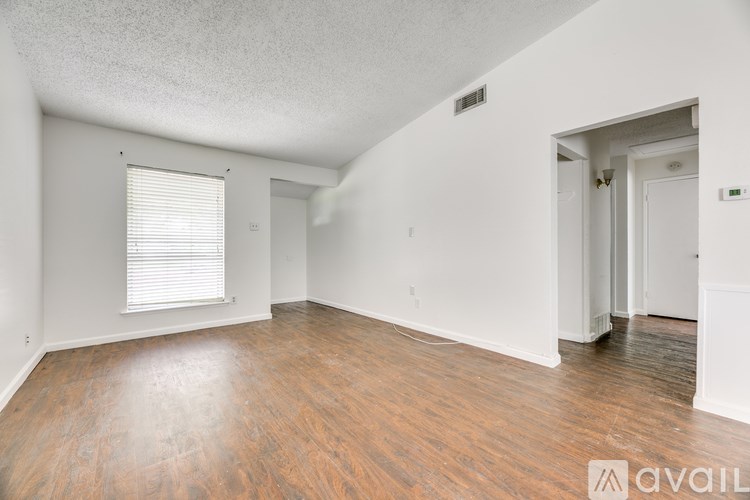 A spacious room with wooden floors and white walls.