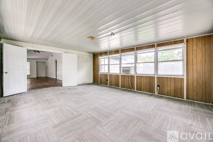 A large, empty room with a carpeted floor and wooden walls.