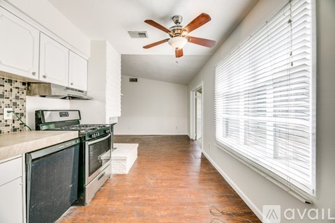 A kitchen with a fan and wooden floors.
