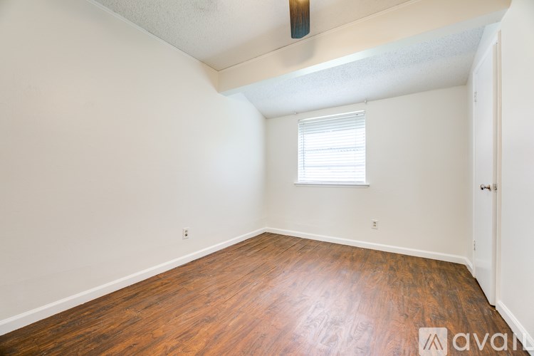 A room with wooden floors and a window with blinds.