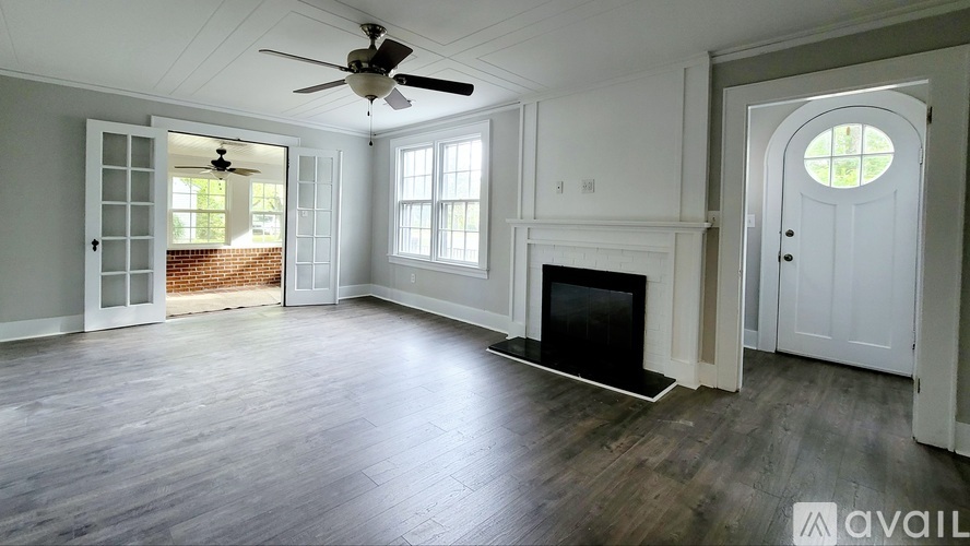 A spacious living room with a fireplace and a ceiling fan.
