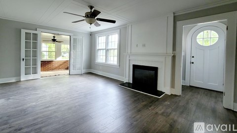 A spacious living room with a fireplace and a ceiling fan.
