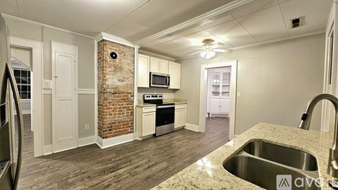 A kitchen with a brick column in the middle of the room.
