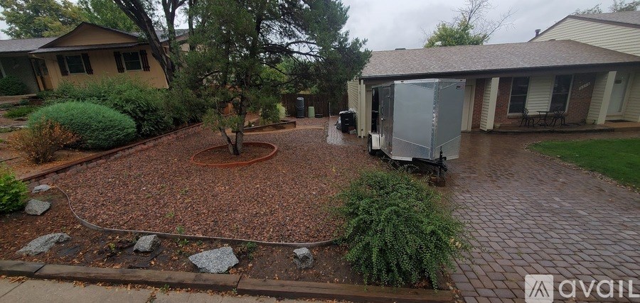 A backyard with a tree, a small garden, and a patio area.