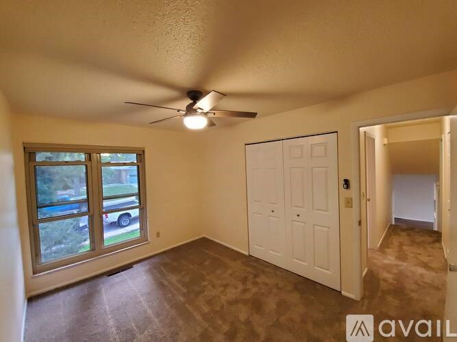 A room with a ceiling fan and a sliding glass door.