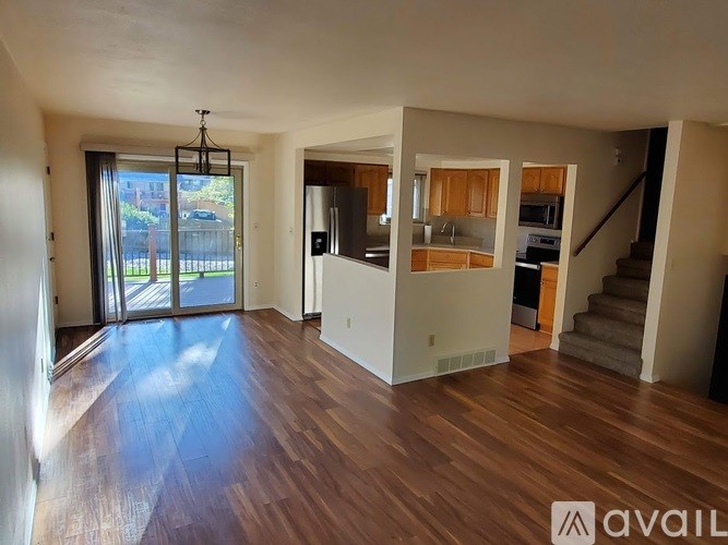 A spacious living room with hardwood floors and a staircase leading to another level.