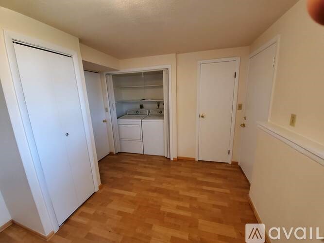 A room with wooden flooring and white walls, with a bed in the middle.