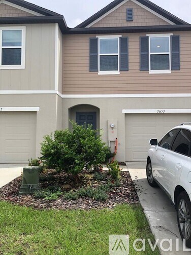 A white car is parked in front of a house.