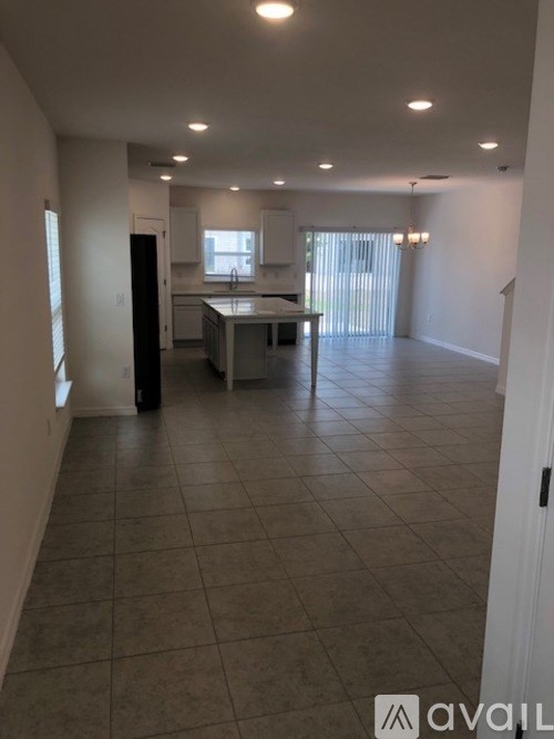 A spacious room with a kitchen area in the background.