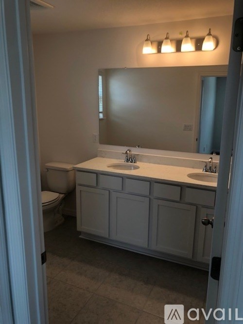 A bathroom with a toilet, sink, and mirror.