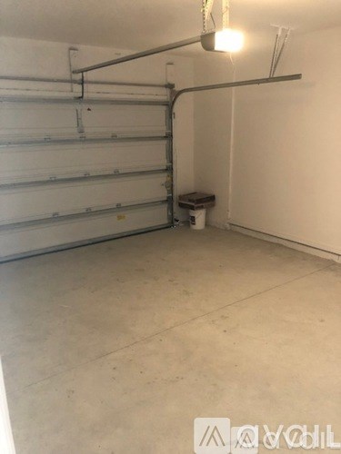 A spacious garage with a white wall and a concrete floor.