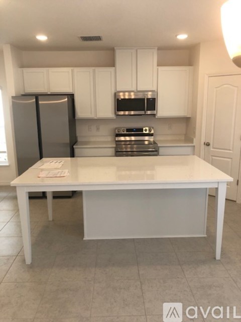 A white kitchen with a table in the middle.