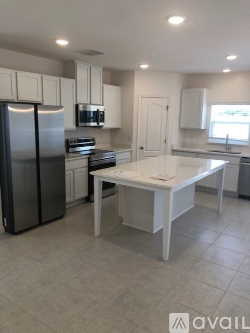 A kitchen with a refrigerator, microwave, oven, and a table.