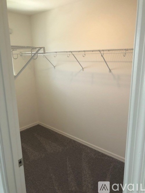 A small, empty room with a carpeted floor and a metal clothes rack.