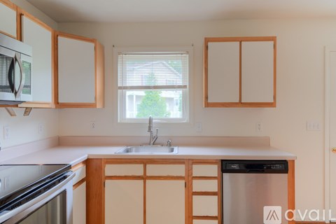 A kitchen with wooden cabinets and a stainless steel dishwasher.