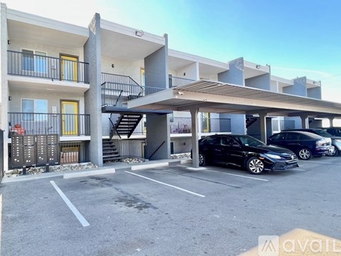 A black car is parked in a parking lot in front of a building.