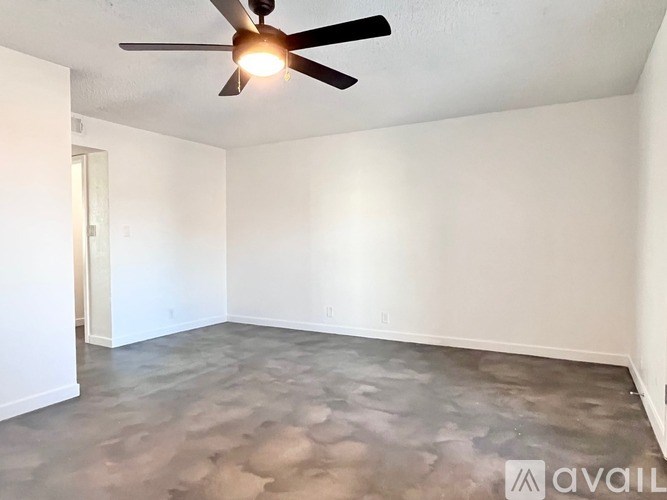 A room with a ceiling fan and a concrete floor.