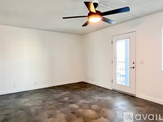 A room with a ceiling fan and a door leading to a hallway.