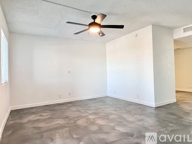 A room with a ceiling fan and a concrete floor.
