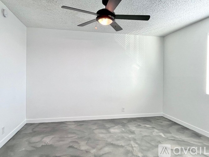 A room with a ceiling fan and a grey floor.