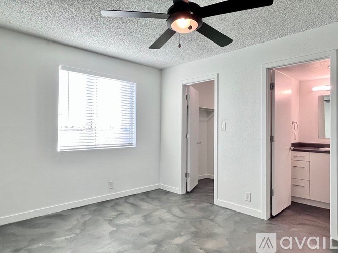 A room with a ceiling fan and a window with blinds.