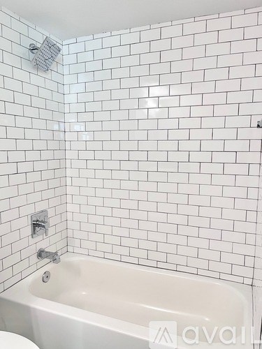 A white bathtub in a bathroom with white tiles.