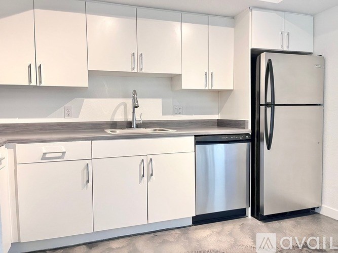 A kitchen with white cabinets and a black refrigerator.
