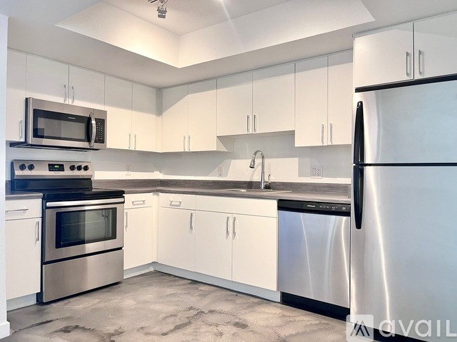 A kitchen with white cabinets and a black fridge.