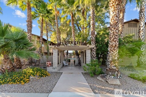 A beautifully landscaped entrance to a condo complex with a clear blue sky above.