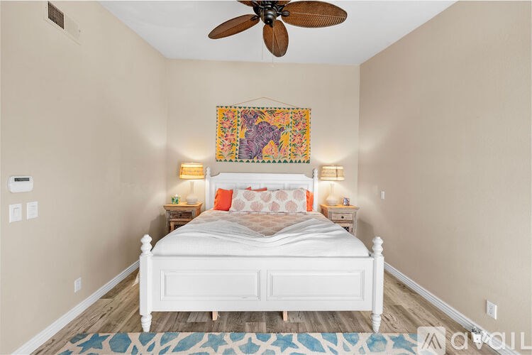 A bedroom with a white bed and a ceiling fan.