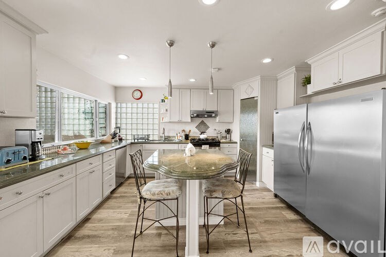 A kitchen with a table and chairs in front of a refrigerator.