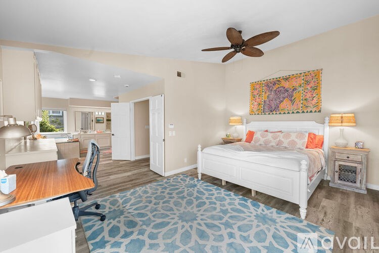 A bedroom with a bed, a chair, and a ceiling fan.