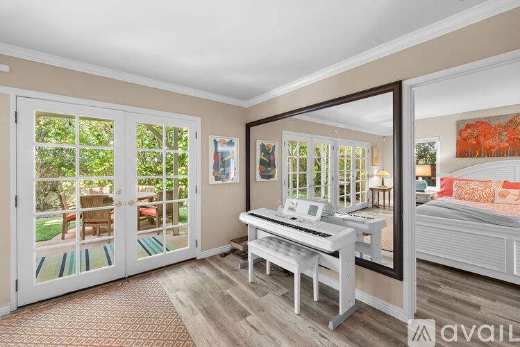 A room with a piano and a bed with a red pillow.