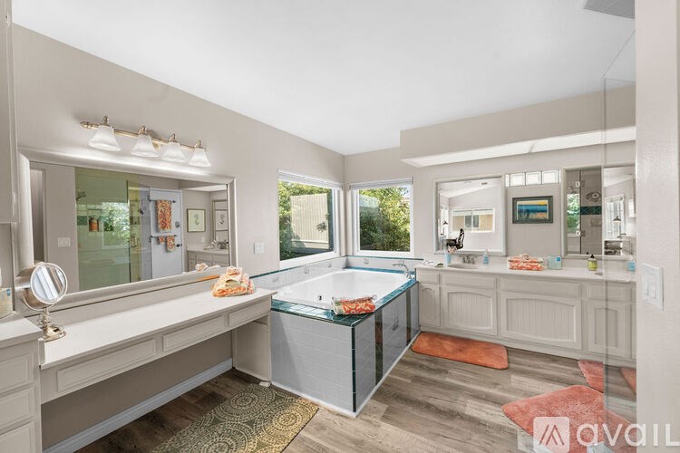 A bathroom with a large mirror, a bathtub, and a vanity.