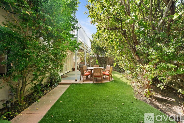 A backyard with a lawn and a table surrounded by trees.