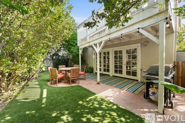 A patio with a table and chairs is surrounded by trees.