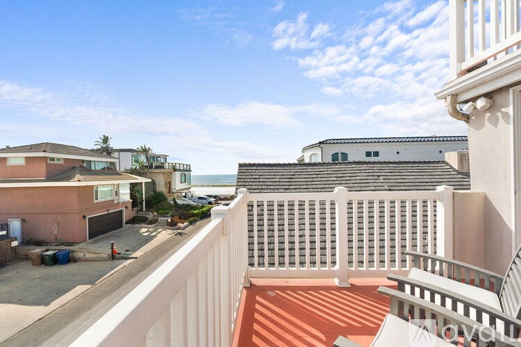A balcony with a white railing overlooks a residential area.