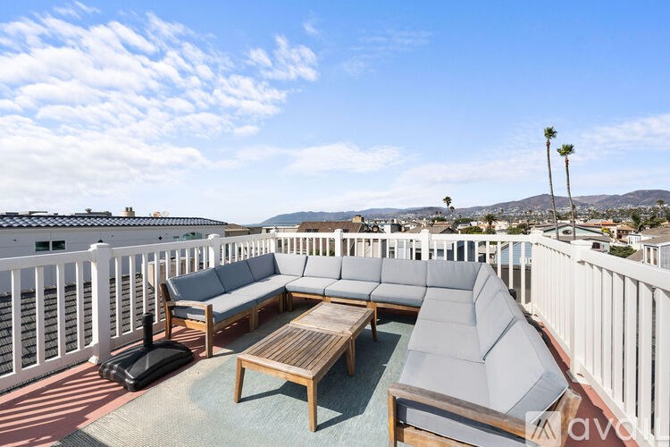 A balcony with a white railing and a grey couch.